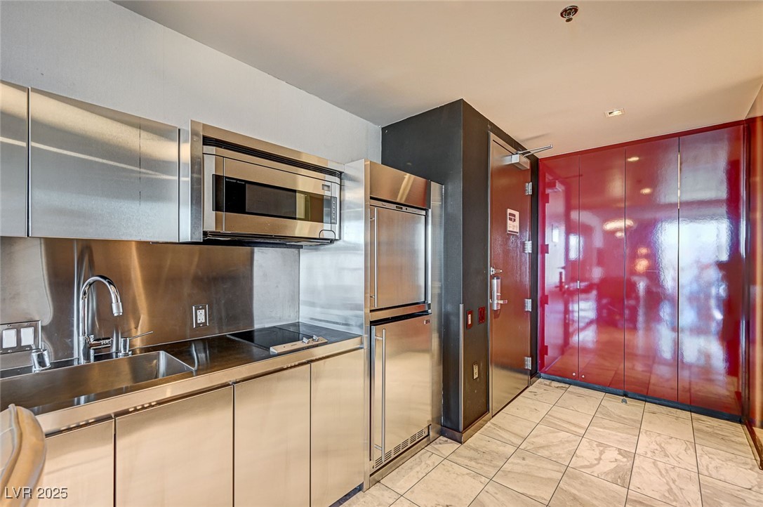 4381 West Flamingo Road, Unit 53307 Las Vegas, NV 89103 - Photo 12 of 45 Kitchen featuring stainless steel microwave, dark countertops, tasteful backsplash, black electric stovetop, and paneled fridge