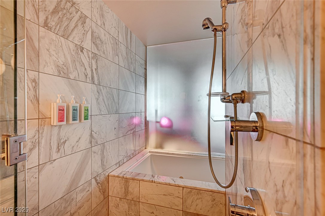 4381 West Flamingo Road, Unit 53307 Las Vegas, NV 89103 - Photo 16 of 45 Bathroom with a garden tub, tiled shower, and tile walls