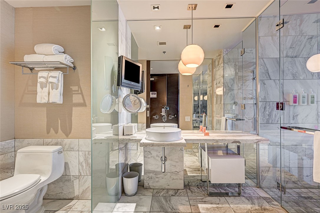 4381 West Flamingo Road, Unit 53307 Las Vegas, NV 89103 - Photo 18 of 45 Bathroom featuring tile walls, a stall shower, and vanity