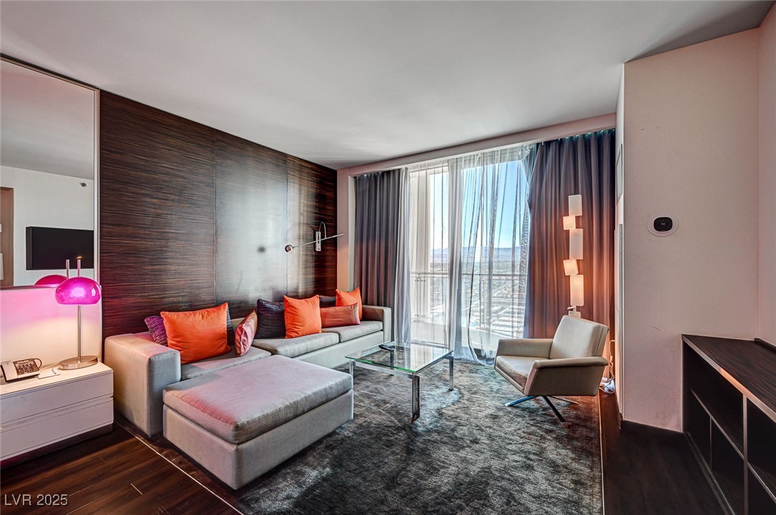 4381 West Flamingo Road, Unit 53307 Las Vegas, NV 89103 - Photo 4 of 45 Living room with dark wood-type flooring, floor to ceiling windows, and an accent wall