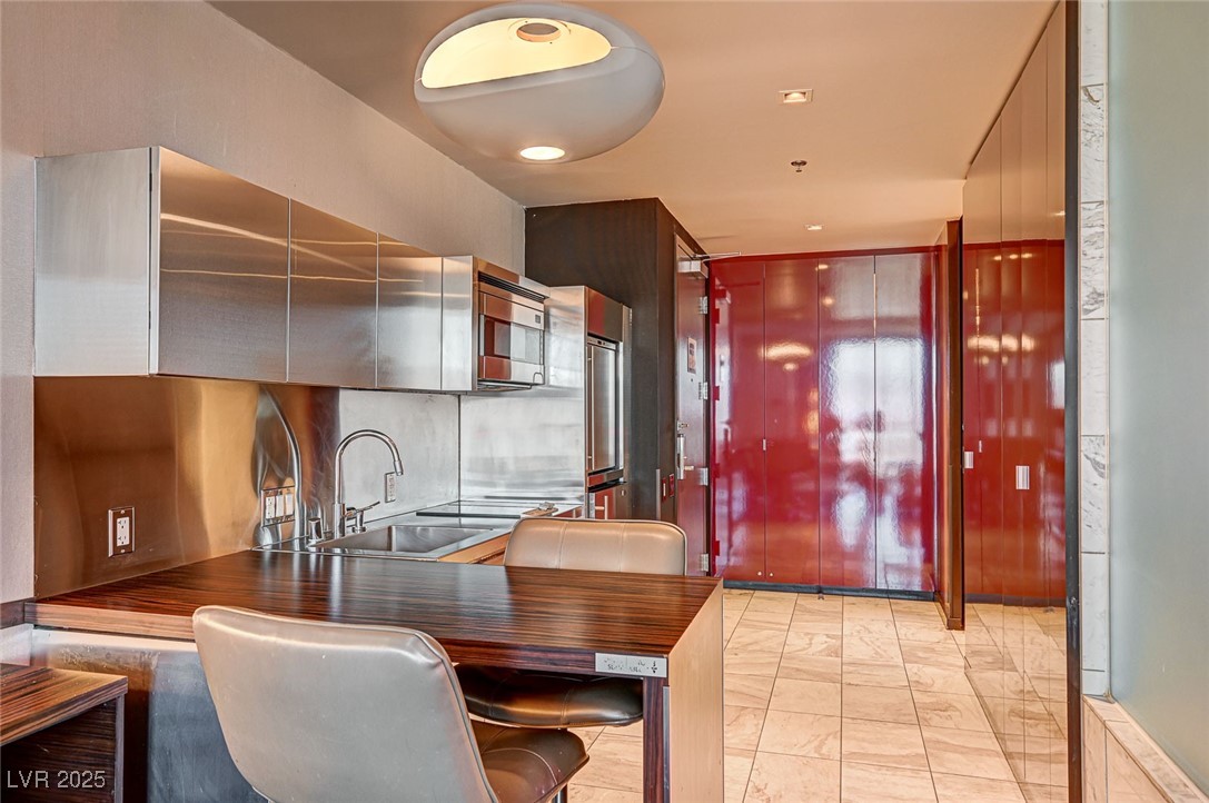 4381 West Flamingo Road, Unit 53307 Las Vegas, NV 89103 - Photo 10 of 45 Kitchen featuring a kitchen breakfast bar, stainless steel appliances, a peninsula, wood counters, and modern cabinets
