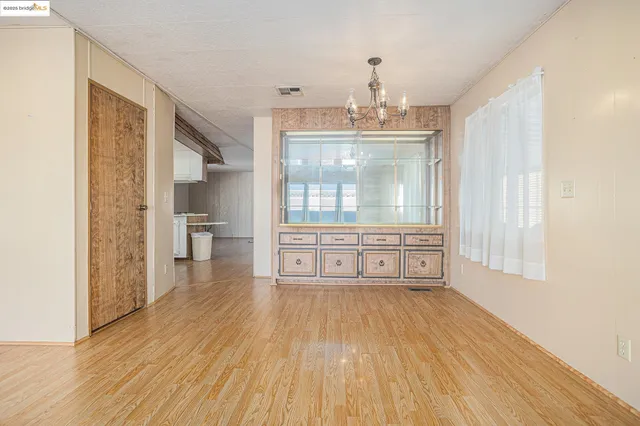 a view of an empty room with window and wooden floor