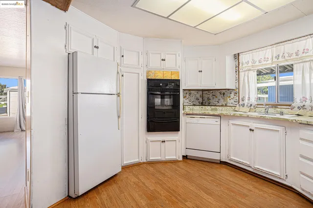a kitchen with stainless steel appliances a stove a sink and white cabinets