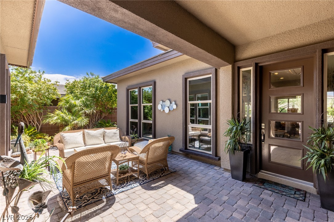 An inviting covered patio featuring wicker furniture and lush landscaping, perfect for al fresco relaxation.