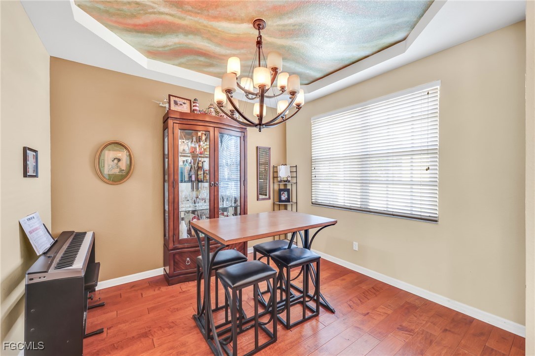 14067 Danpark Loop Fort Myers, FL 33912 - Photo 5 of 41 a dining room with wooden floor a chandelier a wooden table and chairs