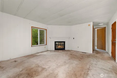 an empty room with windows and fireplace