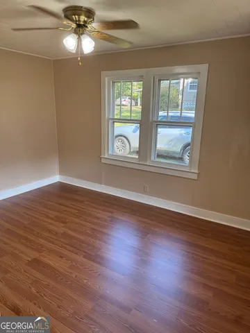 a view of an empty room with wooden floor and window