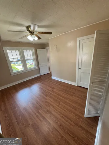 an empty room with wooden floor fan and windows