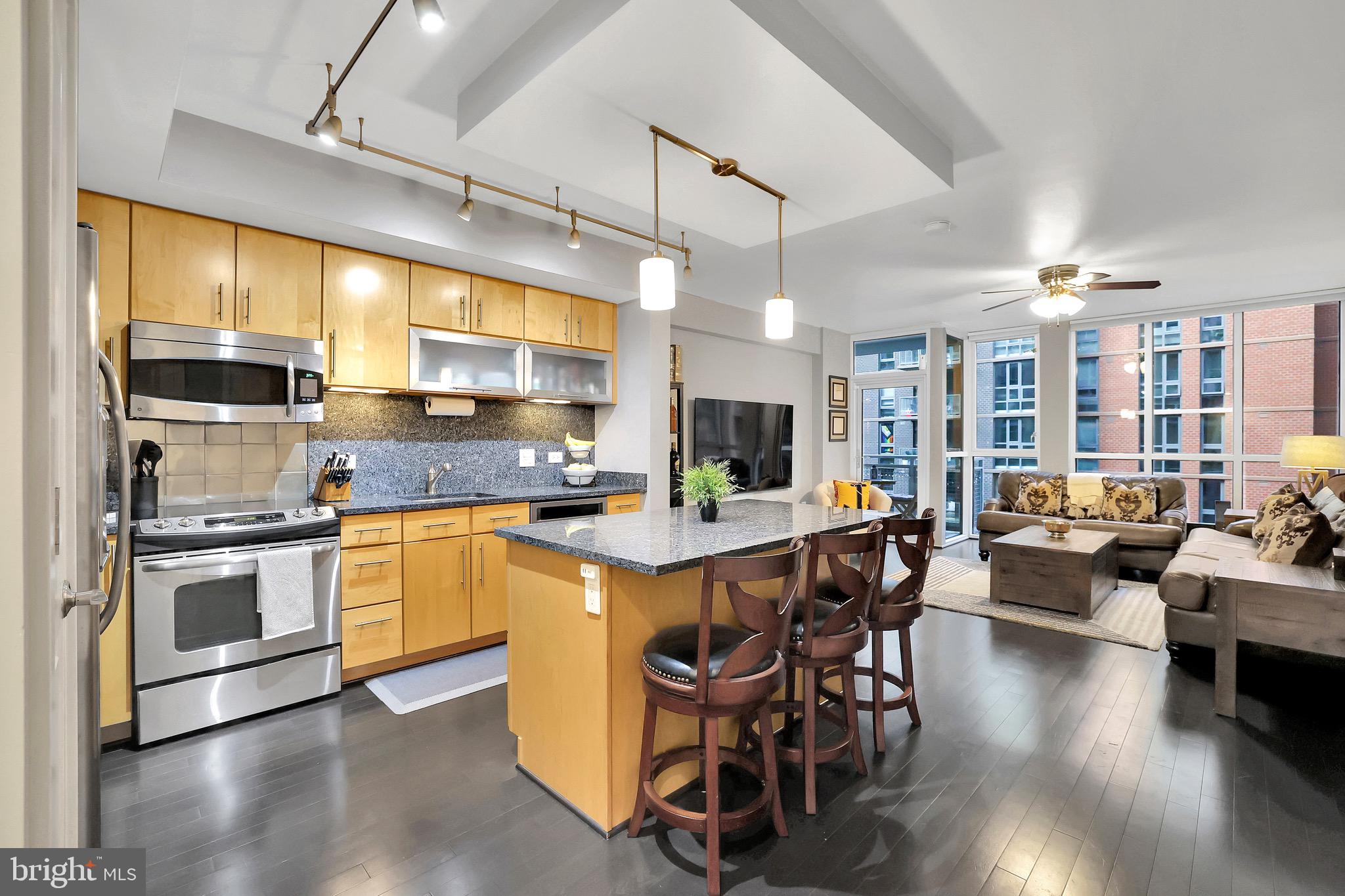 1025 First Street Southeast, Unit 602 Washington, DC 20003 - Photo 2 of 49 a kitchen with stainless steel appliances granite countertop a stove a refrigerator a kitchen island a dining table and chairs with wooden floor