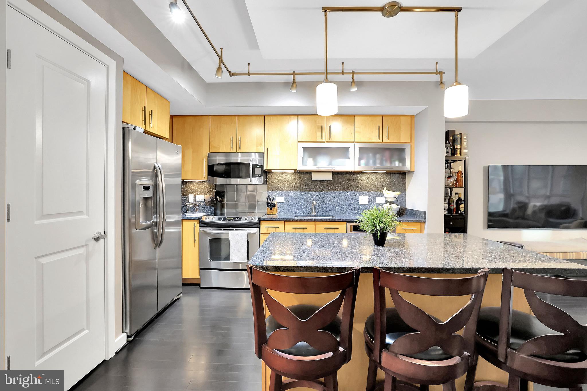 1025 First Street Southeast, Unit 602 Washington, DC 20003 - Photo 7 of 49 a kitchen with stainless steel appliances granite countertop a stove a refrigerator a sink a dining table and chairs with wooden floor