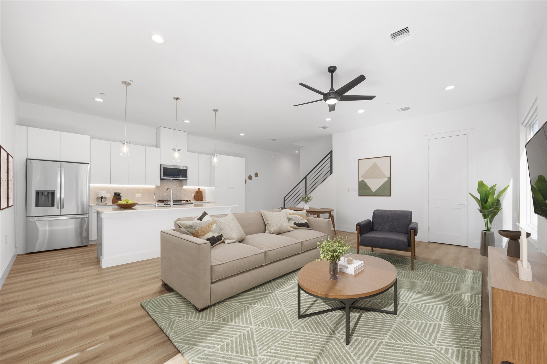 a living room with furniture kitchen view and a wooden floor