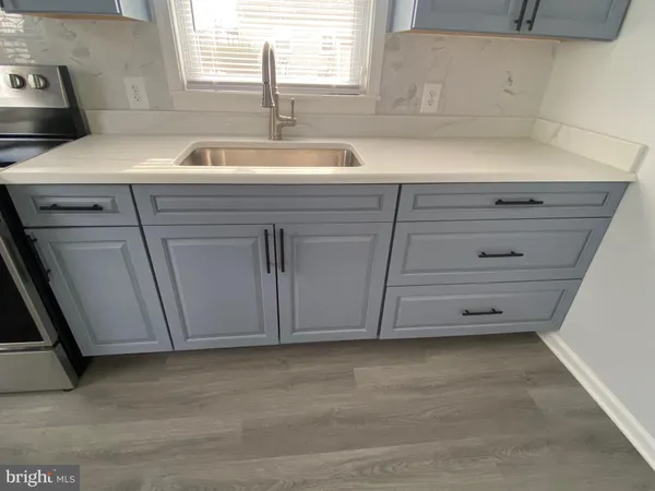 a view of a kitchen with a sink and dishwasher a stove with wooden floor