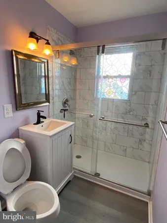 a bathroom with a granite countertop sink mirror vanity and toilet