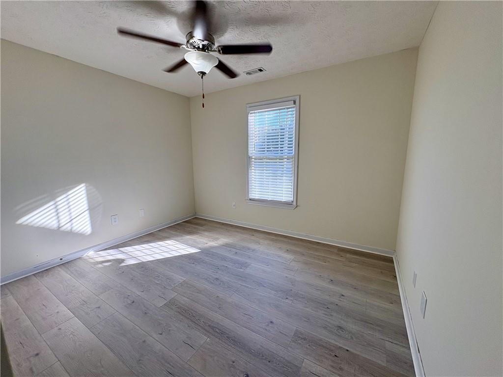 208 Maple Street Dawsonville, GA 30534 - Photo 15 of 21 an empty room with wooden floor ceiling fan and windows