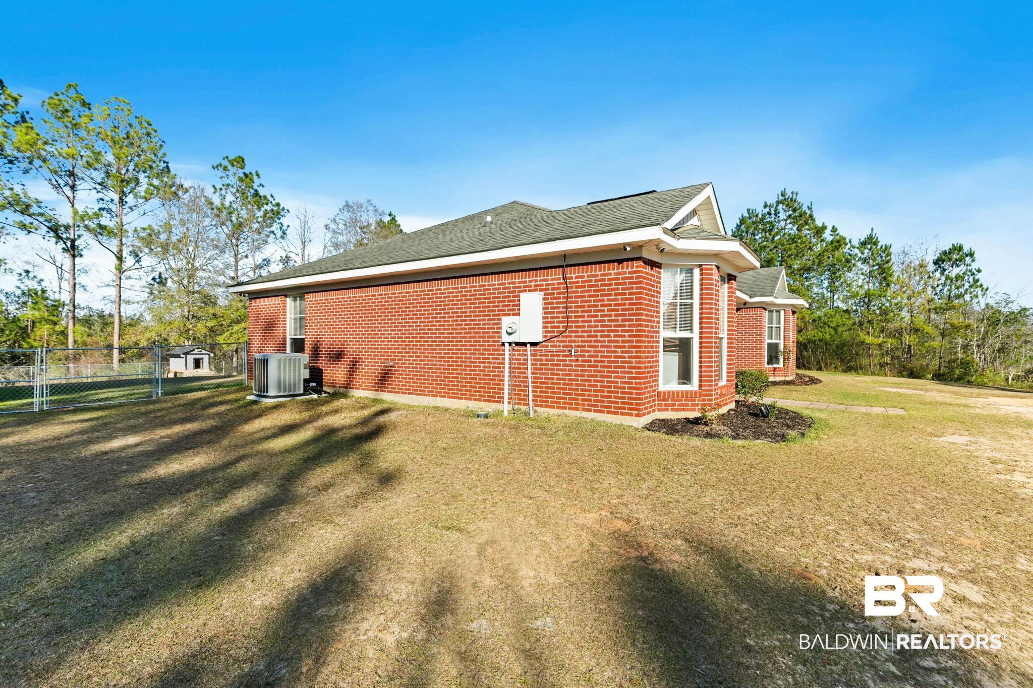 55750 Lottie Road Perdido, AL 36562 - Photo 30 of 84 View of home's exterior featuring a gate, brick siding, and a shingled roof