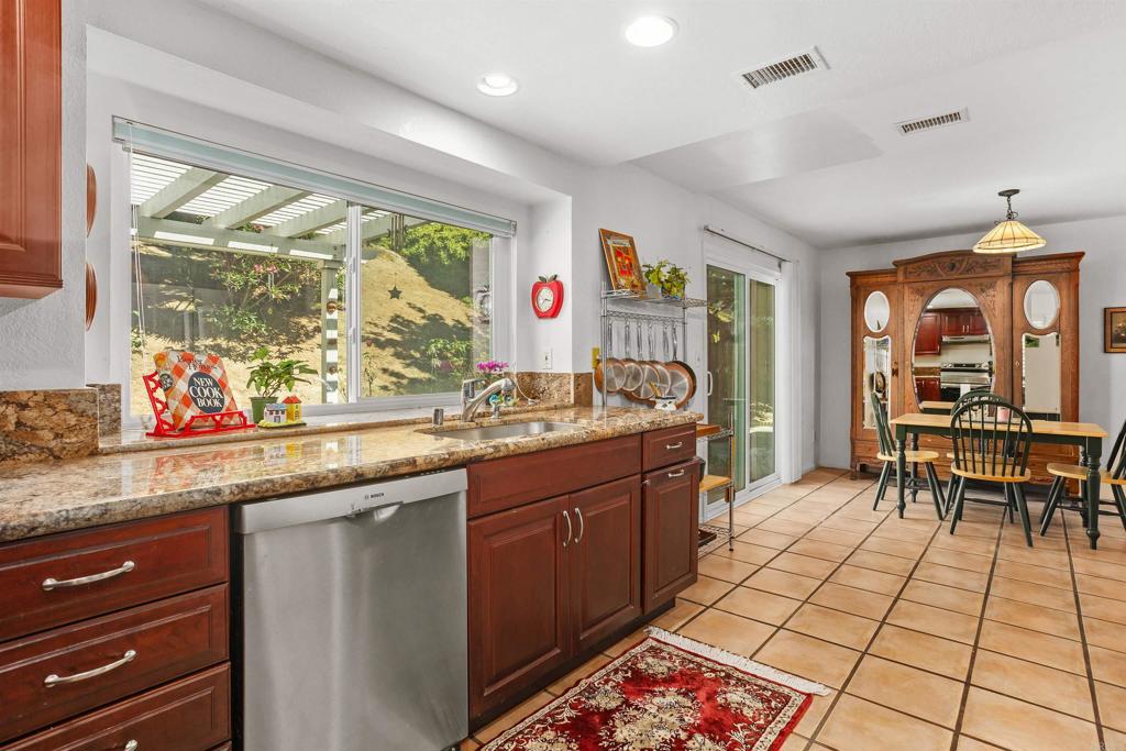1991 Paseo Del Rey Vista, CA 92084 - Photo 19 of 42 a kitchen with stainless steel appliances granite countertop a stove a sink and a dining table with wooden cabinet