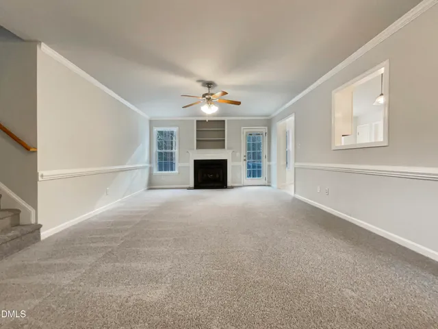 a view of a livingroom with a fireplace a ceiling fan and window