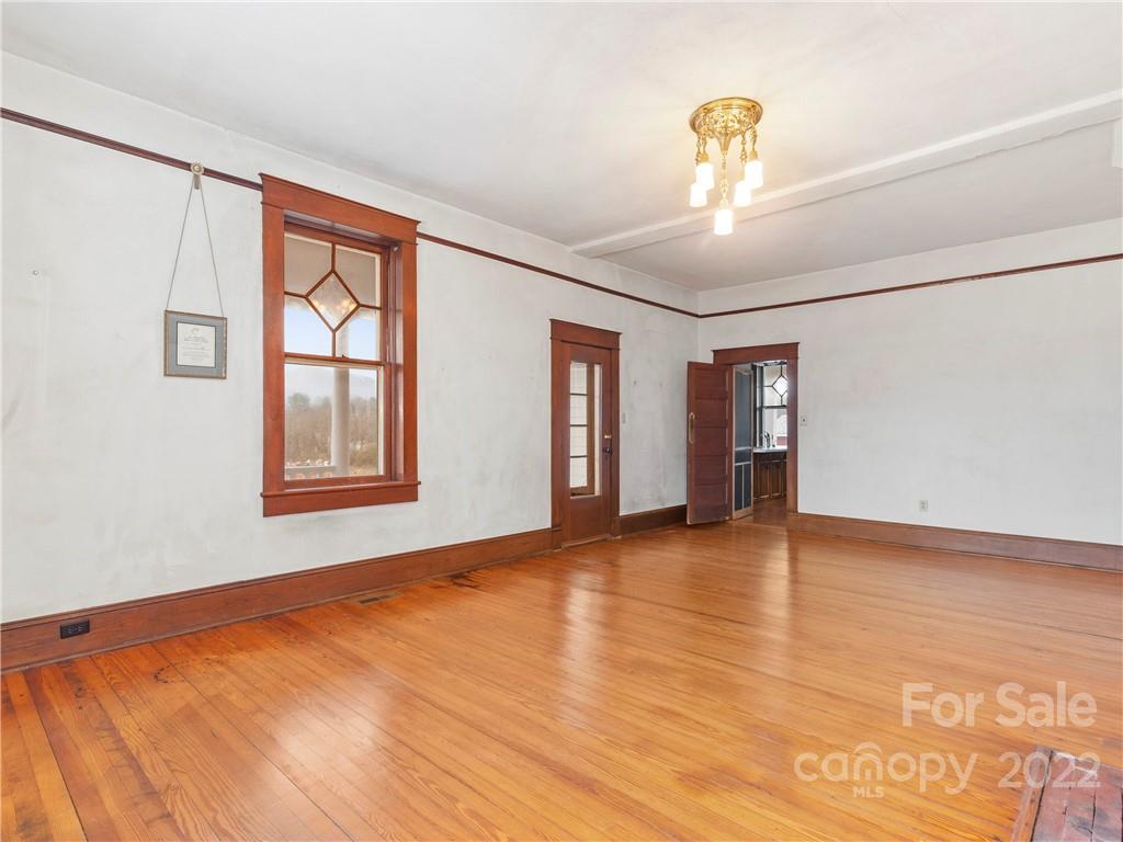 5593 Old Clyde Road Clyde, NC 28721 - Photo 8 of 35 an empty room with wooden floor chandelier and windows