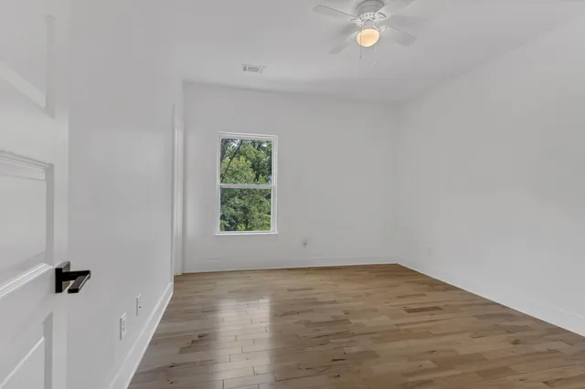 a view of an empty room with wooden floor and a window