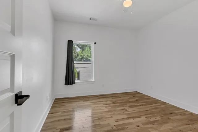 a view of an empty room with wooden floor and a window