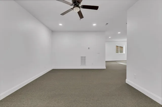 an empty room with a ceiling fan and window