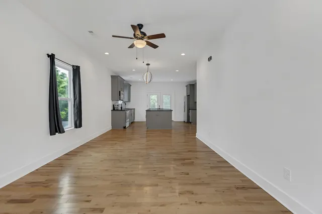 a view of an empty room with kitchen and window