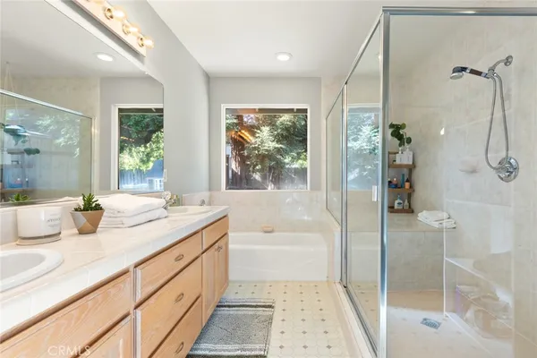a bathroom with a granite countertop sink a mirror a bathtub and next to a window