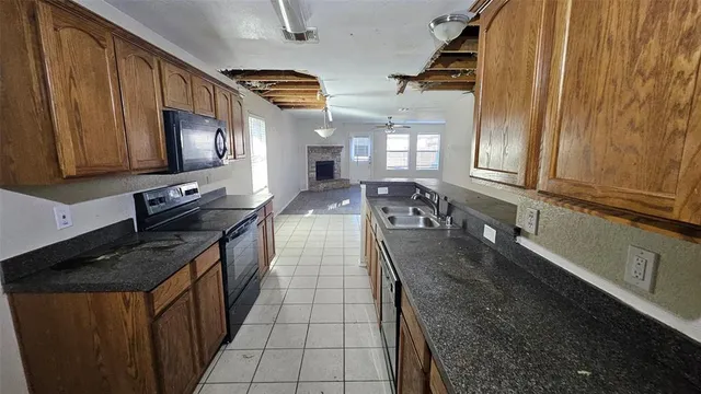 a kitchen with granite countertop a stove a sink and dishwasher wooden cabinets with granite countertops