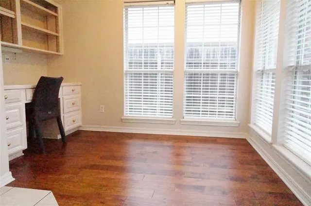 a view of an empty room with a window and wooden floor