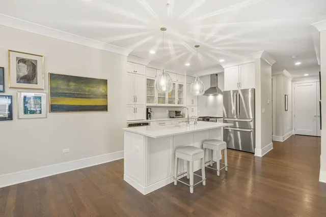 a kitchen with stainless steel appliances granite countertop a refrigerator a stove a sink dishwasher and white cabinets with wooden floor