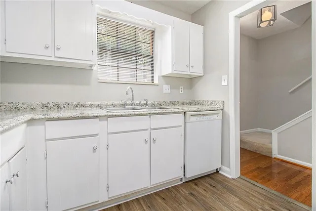 a kitchen with granite countertop white cabinets and a hard wood floor