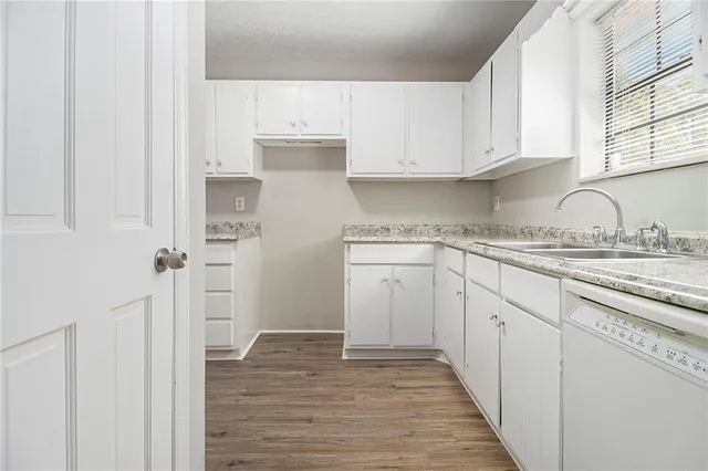 a kitchen with granite countertop white cabinets and white appliances