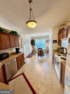 a kitchen with stainless steel appliances granite countertop a stove top oven a sink dishwasher and white cabinets with wooden floor