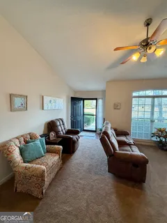 a living room with furniture a ceiling fan and a window