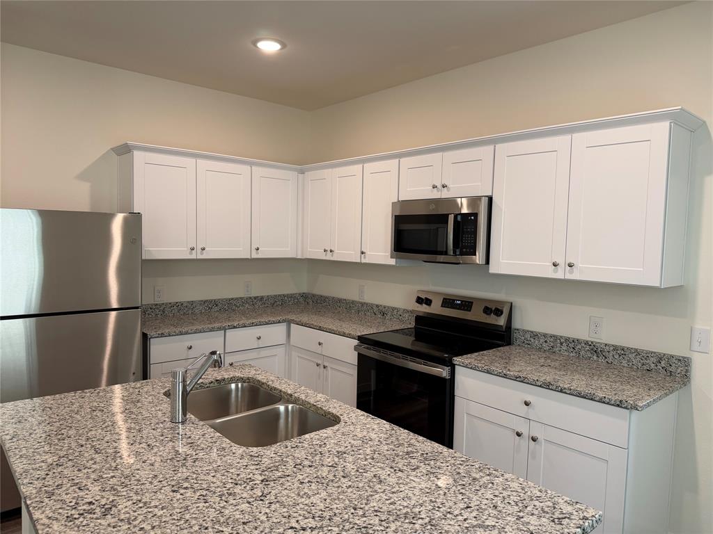 609 Merced River Lane Anna, TX 75409 - Photo 7 of 27 a kitchen with granite countertop a sink stove and microwave