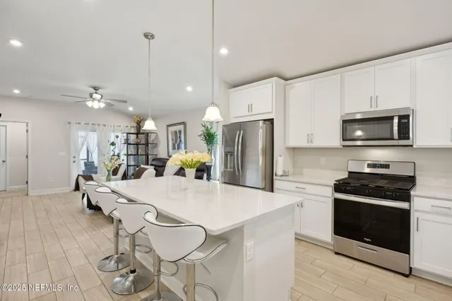 a kitchen with stainless steel appliances kitchen island granite countertop a refrigerator a stove a microwave oven a sink with island and chairs