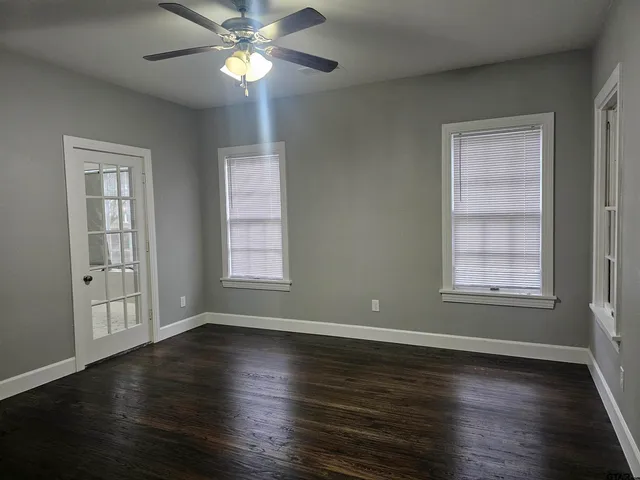 a view of an empty room with wooden floor and a window