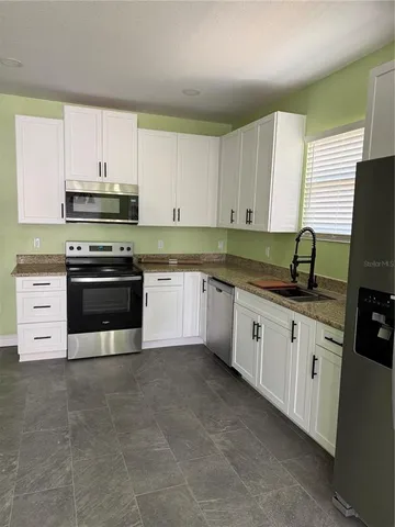 a kitchen with stainless steel appliances granite countertop a stove a sink and a microwave