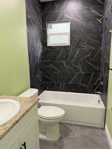 a bathroom with a granite countertop toilet a sink and a bathtub