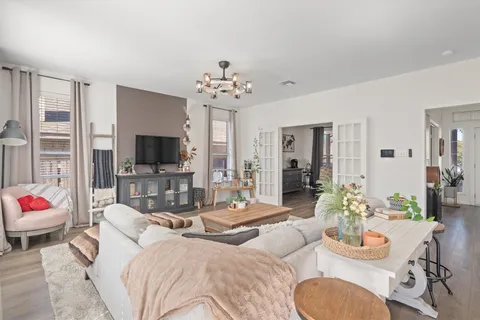 a living room with furniture a flat screen tv and a chandelier