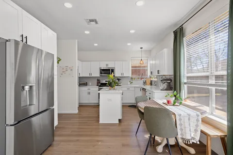 a large kitchen with white cabinets stainless steel appliances and a dining table