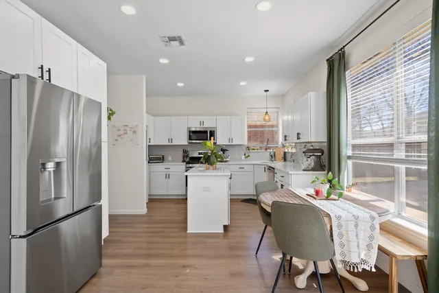 a large kitchen with white cabinets stainless steel appliances and a dining table