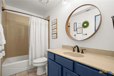 a bathroom with a sink a mirror a toilet and a window