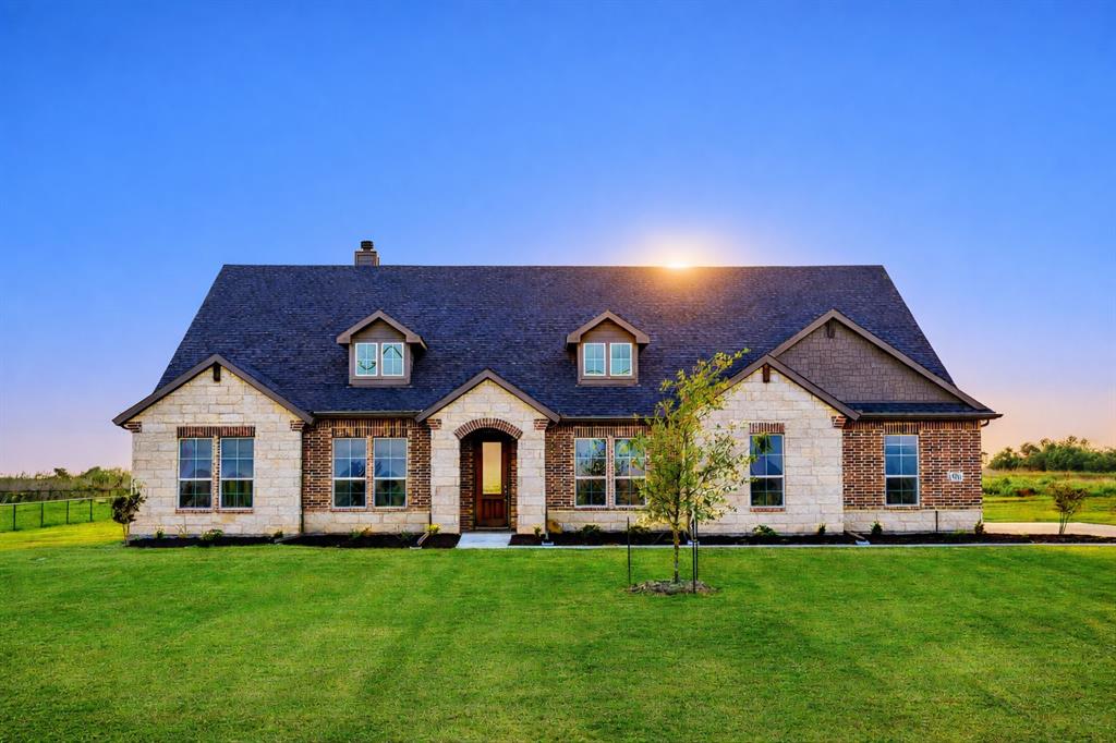 Stone and brick facade with a dark shingle roof and dormer windows