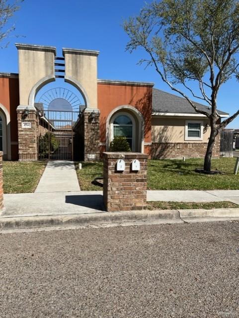 4708 North Cypress Street Pharr, TX 78577 - Photo 3 of 10 View of front facade with a gate, fence, brick siding, and stucco siding