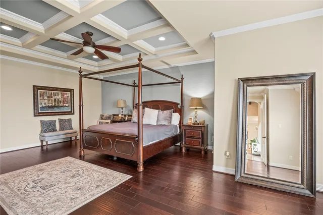 a bedroom with a bed wooden floor and view of kitchen