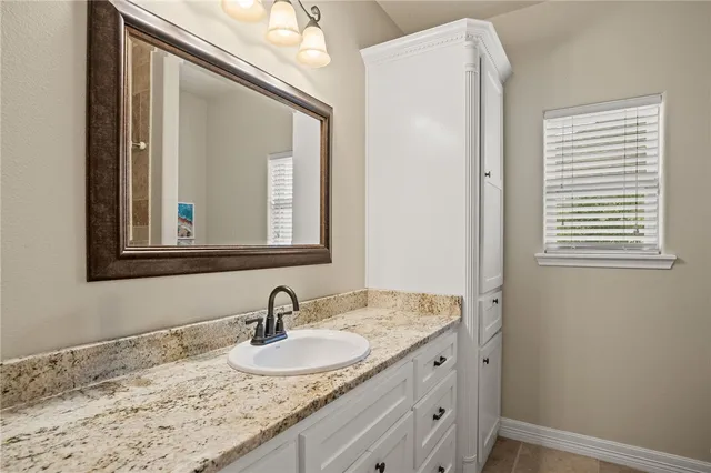 a bathroom with a granite countertop sink and a mirror