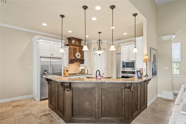 a kitchen with kitchen island granite countertop a sink a counter top space stainless steel appliances and cabinets