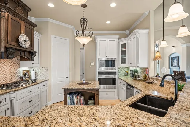 a kitchen with stainless steel appliances kitchen island granite countertop a stove a sink and a refrigerator