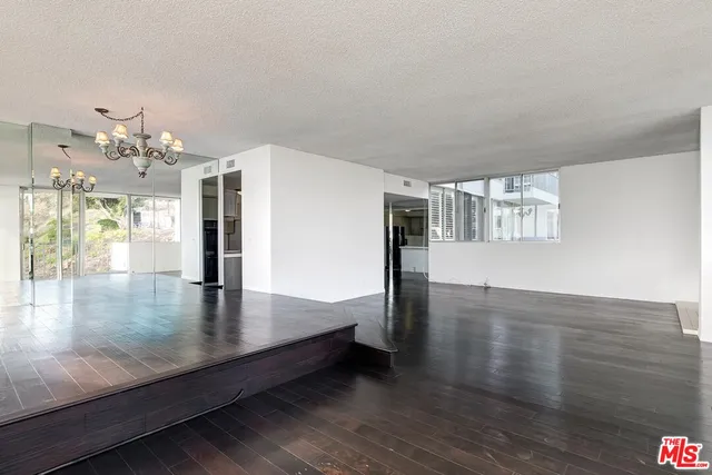 a view of a big room with wooden floor and a kitchen